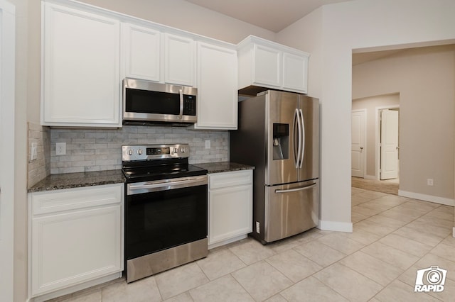 kitchen with stainless steel appliances, white cabinets, and dark stone counters