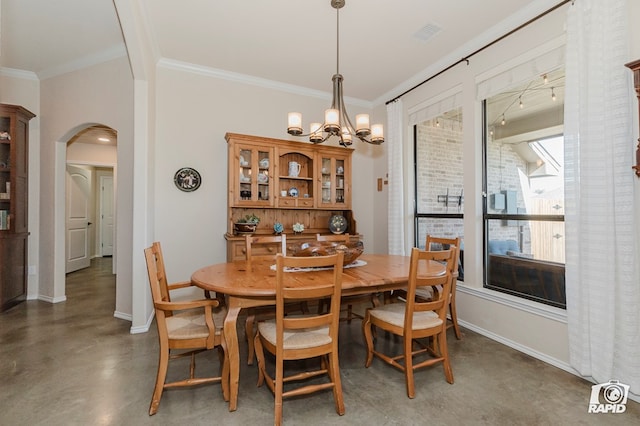 dining room featuring arched walkways, ornamental molding, a chandelier, baseboards, and finished concrete floors