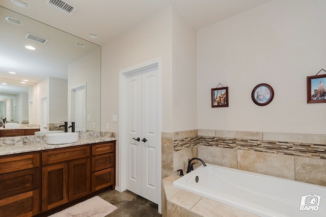 bathroom featuring a garden tub, vanity, and recessed lighting