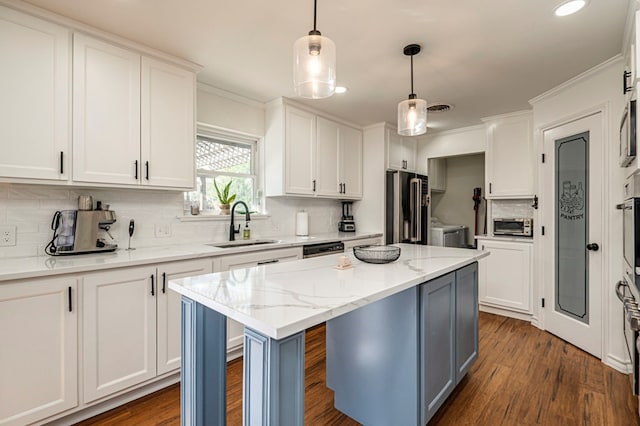 kitchen with appliances with stainless steel finishes, white cabinets, hanging light fixtures, and a center island