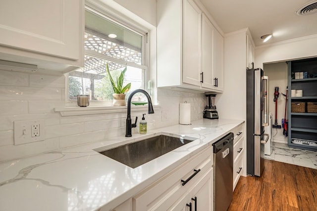 kitchen with white cabinetry, appliances with stainless steel finishes, backsplash, light stone counters, and sink