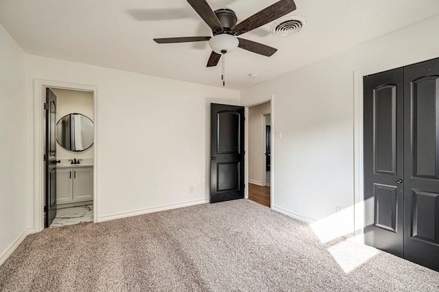 unfurnished bedroom with light carpet, ensuite bath, ceiling fan, and a closet