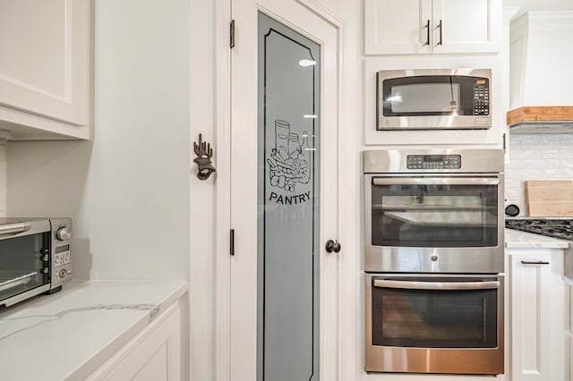 kitchen featuring light stone countertops, appliances with stainless steel finishes, tasteful backsplash, and white cabinetry