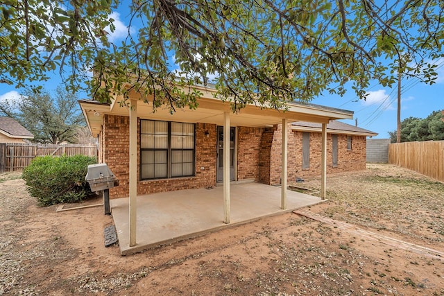 back of house with a patio, brick siding, and a fenced backyard