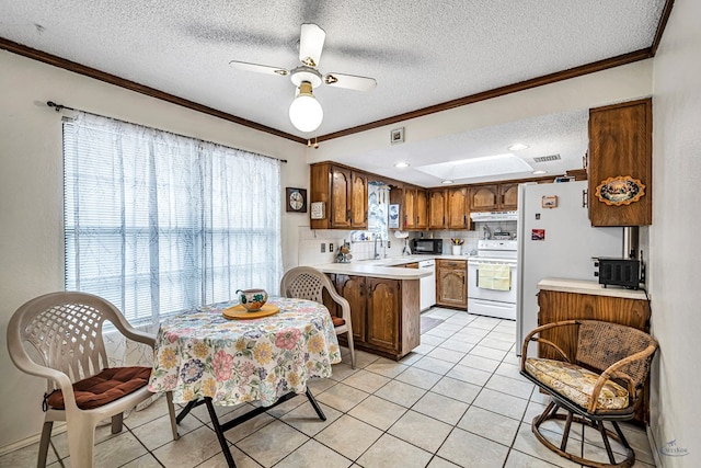 kitchen with white appliances, brown cabinets, a peninsula, light countertops, and under cabinet range hood