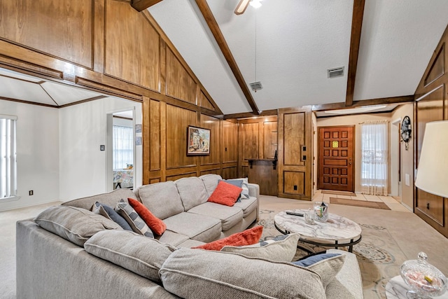 living area with a wealth of natural light, beamed ceiling, visible vents, and wooden walls