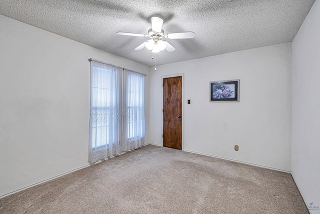 empty room with a ceiling fan, light carpet, and a textured ceiling