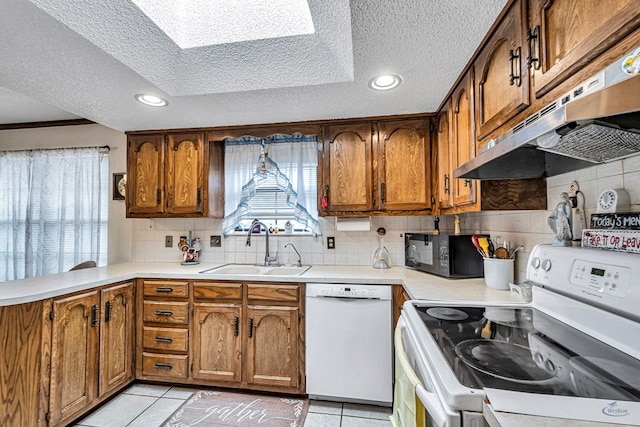 kitchen featuring brown cabinets, white appliances, under cabinet range hood, and light countertops