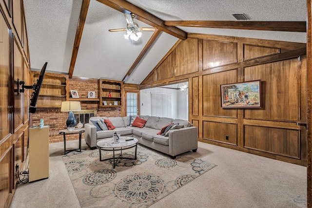 living room featuring vaulted ceiling with beams, light colored carpet, ceiling fan, wooden walls, and a textured ceiling