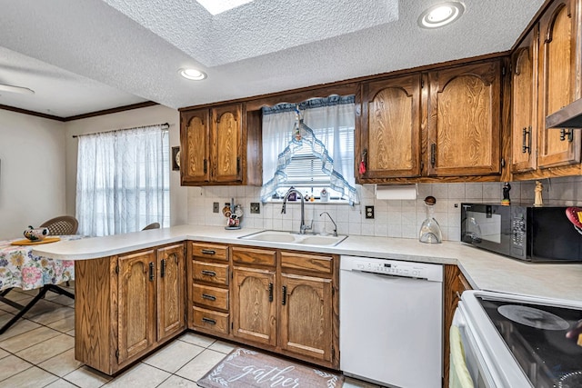 kitchen with dishwasher, a peninsula, light countertops, black microwave, and a sink