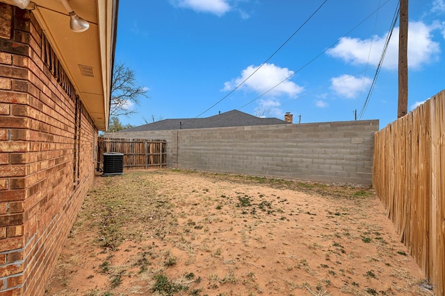 view of yard with a fenced backyard and central AC