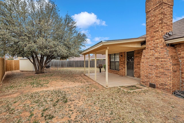 view of yard with a patio area, a fenced backyard, a storage unit, and an outdoor structure