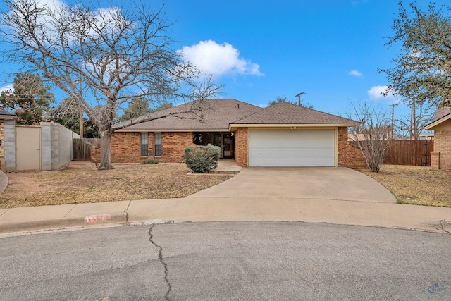 ranch-style house with a garage, concrete driveway, brick siding, and fence