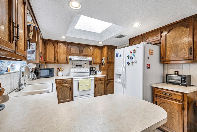 kitchen with white appliances, visible vents, light countertops, under cabinet range hood, and a sink