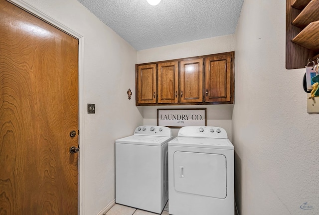 laundry room with washing machine and dryer, cabinet space, a textured ceiling, and light tile patterned floors