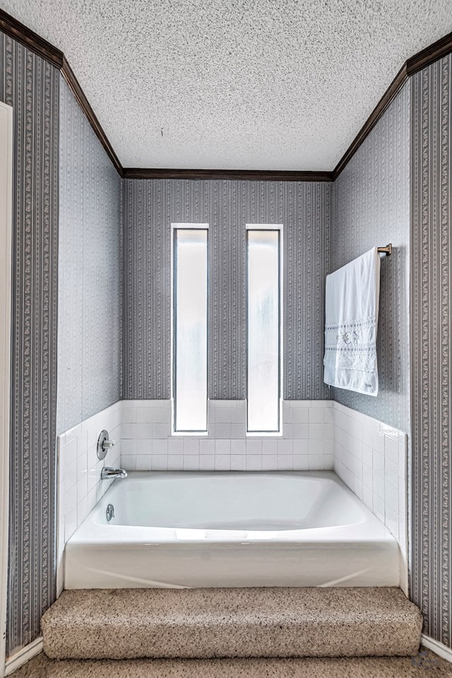 bathroom with a garden tub, crown molding, a textured ceiling, and wallpapered walls