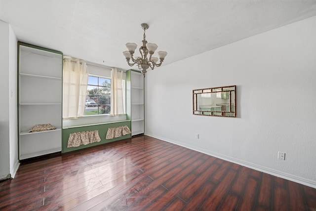 spare room with baseboards, a textured ceiling, wood finished floors, and a notable chandelier