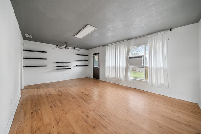 unfurnished living room featuring a ceiling fan, a textured ceiling, baseboards, and wood finished floors