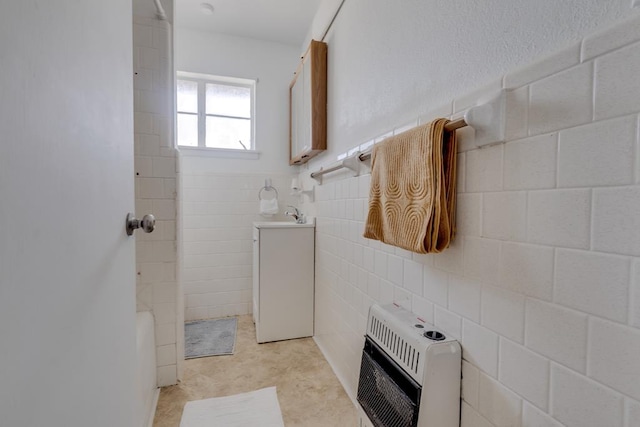 bathroom featuring tile walls, heating unit, shower / bathtub combination, wainscoting, and vanity