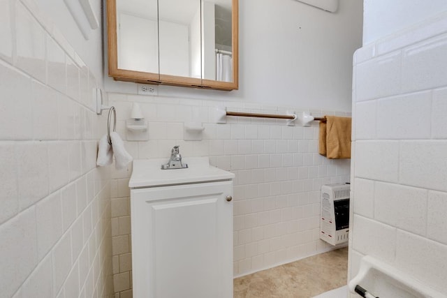 bathroom featuring heating unit, tile patterned flooring, tile walls, and a sink