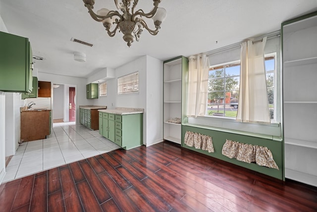 kitchen with light countertops, visible vents, light wood-style flooring, green cabinets, and a chandelier