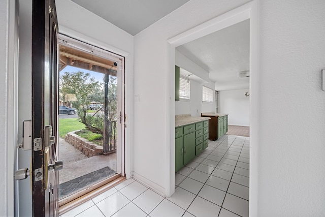 doorway to outside with baseboards and light tile patterned flooring