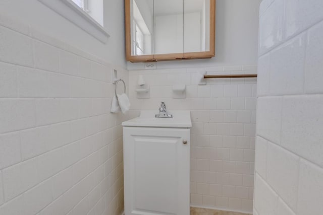 bathroom with a wainscoted wall, a sink, and tile walls