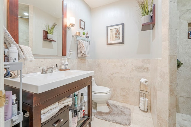 bathroom featuring toilet, vanity, tile walls, and tile patterned floors