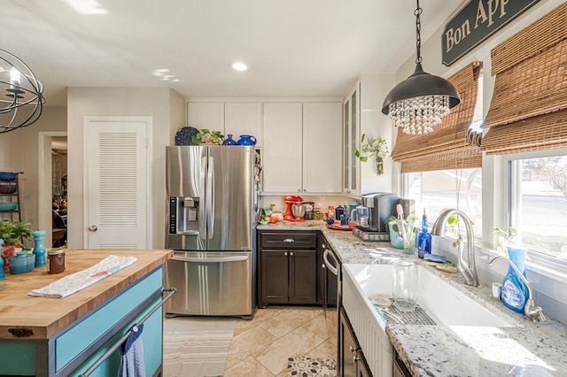 kitchen featuring butcher block counters, appliances with stainless steel finishes, hanging light fixtures, white cabinets, and sink