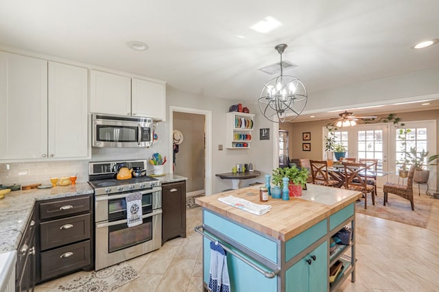 kitchen featuring a center island, decorative light fixtures, white cabinetry, stainless steel appliances, and tasteful backsplash