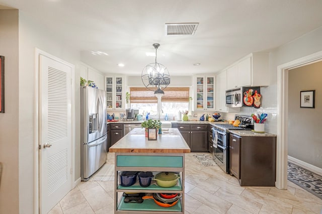 kitchen featuring pendant lighting, a center island, white cabinetry, stainless steel appliances, and a notable chandelier