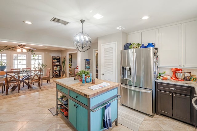 kitchen with a kitchen island, pendant lighting, stainless steel refrigerator with ice dispenser, white cabinetry, and butcher block counters