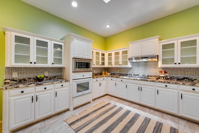 kitchen with decorative backsplash, light tile patterned flooring, white cabinetry, and stainless steel appliances