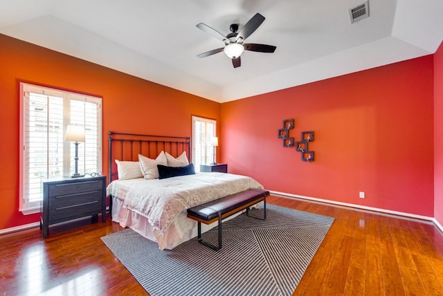 bedroom featuring ceiling fan, dark hardwood / wood-style floors, and a tray ceiling