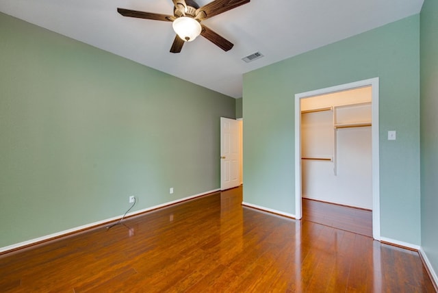 unfurnished bedroom with hardwood / wood-style floors, ceiling fan, a walk in closet, and a closet