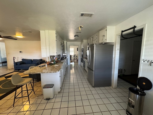 2408 Camarie Ave, Midland, TX 79705 - kitchen with freestanding refrigerator, white cabinetry, open floor plan, and light tile patterned flooring