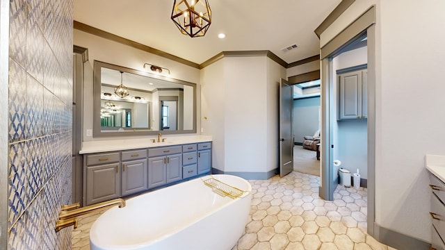 bathroom with vanity, a freestanding bath, baseboards, crown molding, and recessed lighting