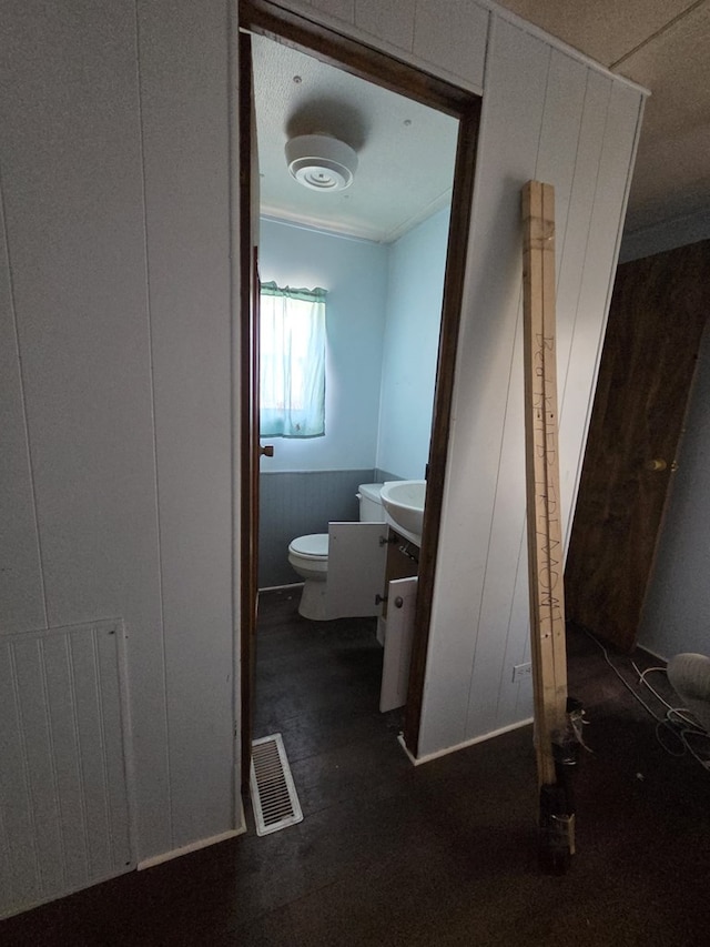 6208 E County Rd 84, Midland, TX 79706 - bathroom featuring vanity, toilet, radiator, and a wainscoted wall