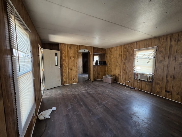 6208 E County Rd 84, Midland, TX 79706 - unfurnished room featuring arched walkways, dark wood-style floors, and wooden walls