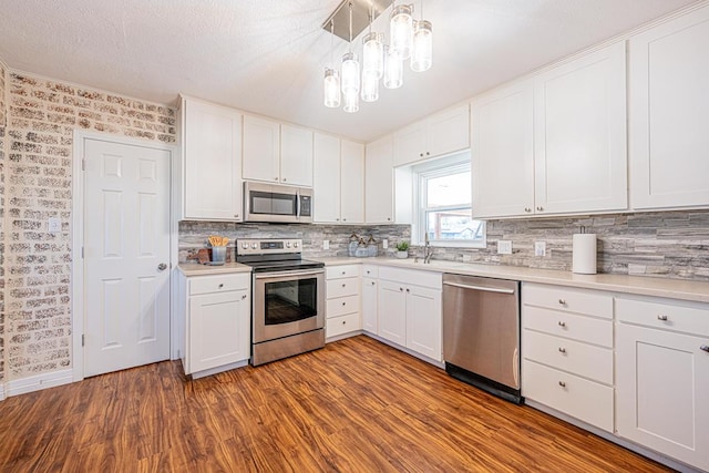 kitchen featuring light countertops, appliances with stainless steel finishes, dark wood finished floors, and an inviting chandelier