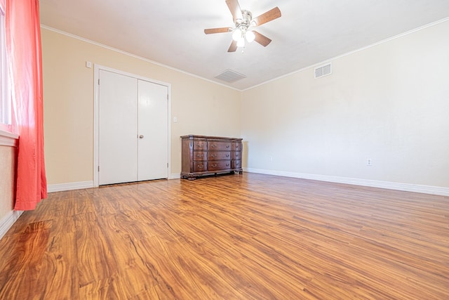 unfurnished bedroom with ornamental molding, visible vents, baseboards, and wood finished floors