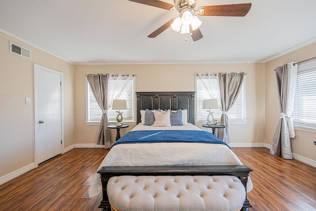 bedroom with baseboards, crown molding, visible vents, and wood finished floors