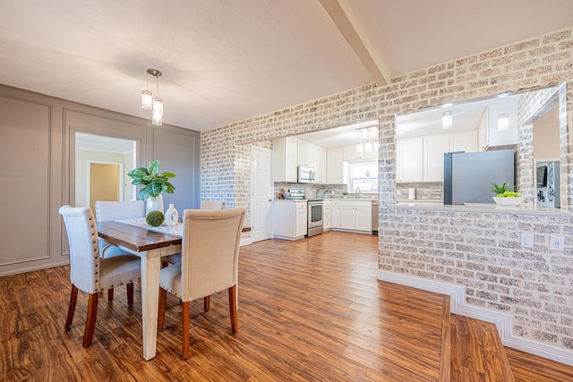 dining room with wood finished floors and beamed ceiling