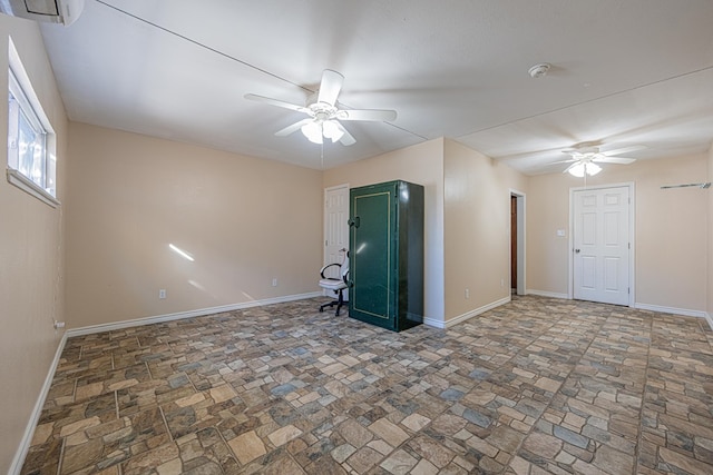 empty room featuring baseboards, a ceiling fan, and a wall mounted AC