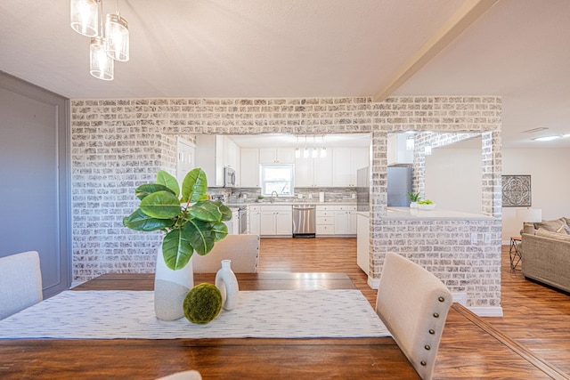 dining area with light wood-style floors and beamed ceiling