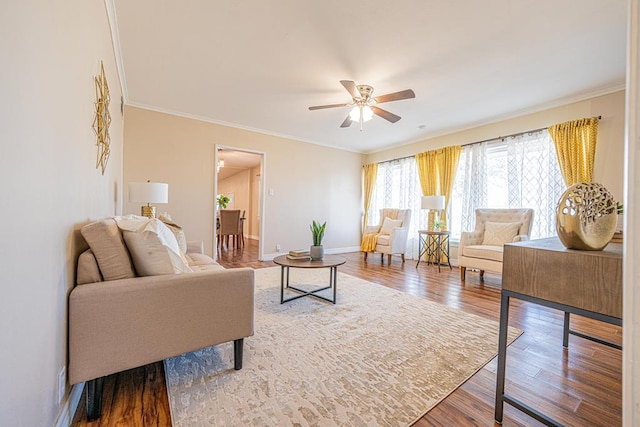 living room with ornamental molding, ceiling fan, baseboards, and wood finished floors