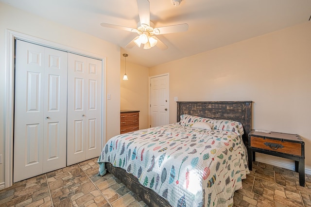 bedroom with a ceiling fan, a closet, and stone tile floors