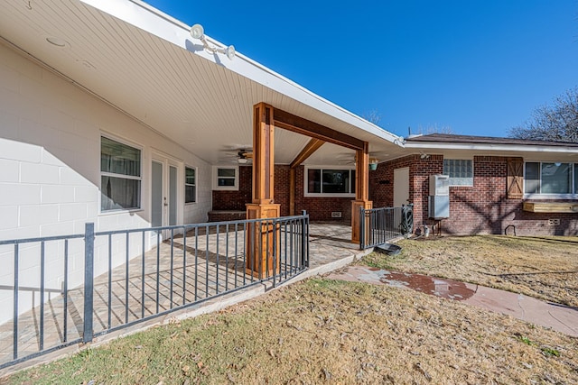 exterior space with concrete block siding, a ceiling fan, and brick siding