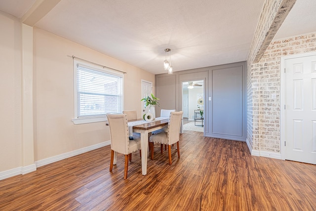 dining area featuring a textured ceiling, wood finished floors, and baseboards