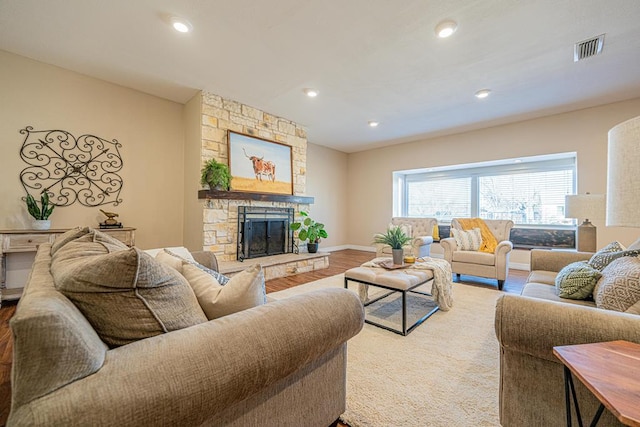 living area with a fireplace, recessed lighting, visible vents, wood finished floors, and baseboards